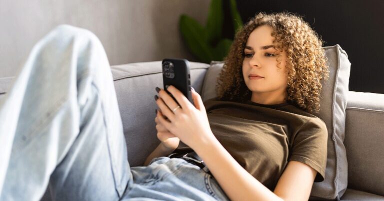 Woman using her phone to learn when to take a pregnancy test after a missed period.
