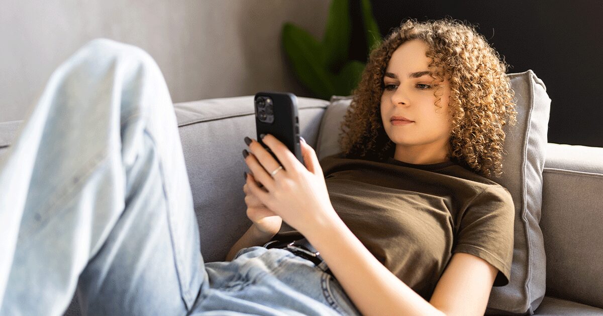 Woman using her phone to learn when to take a pregnancy test after a missed period.